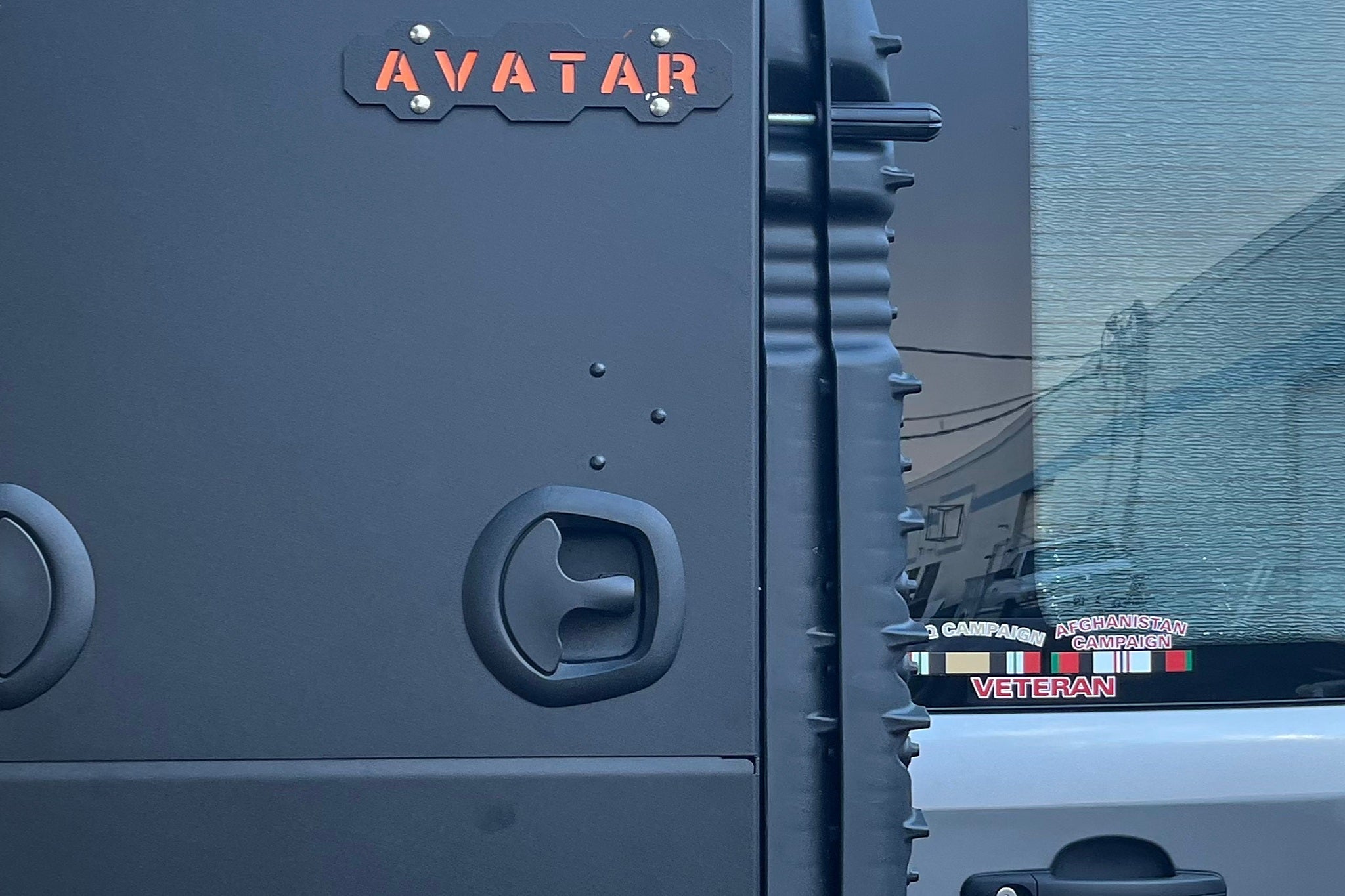 Close view of a matte black powder-coated cargo box mounted on the exterior of a van