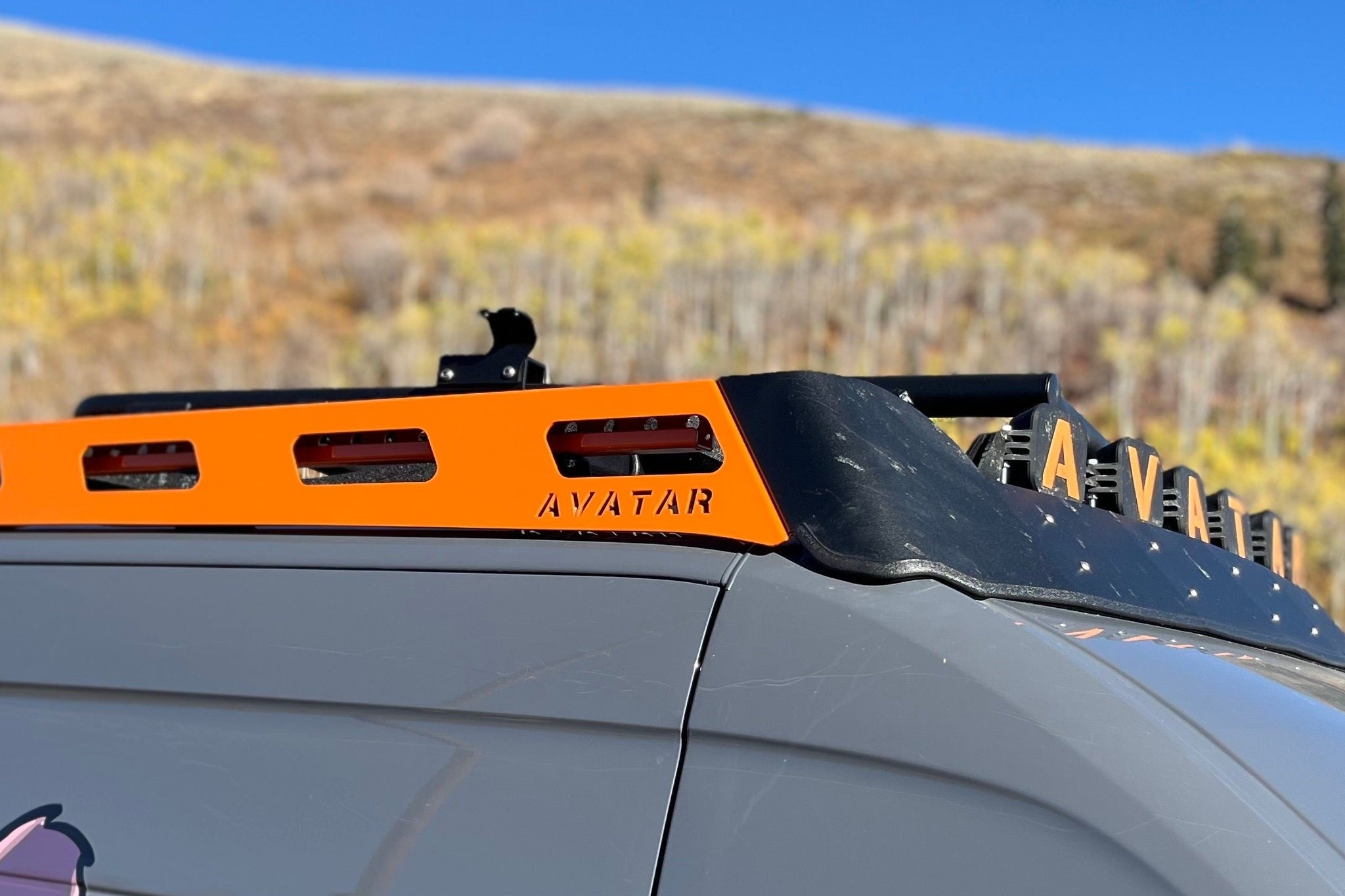 Close view of a low-profile slatted roof platform meeting the roof of a van on visible feet
