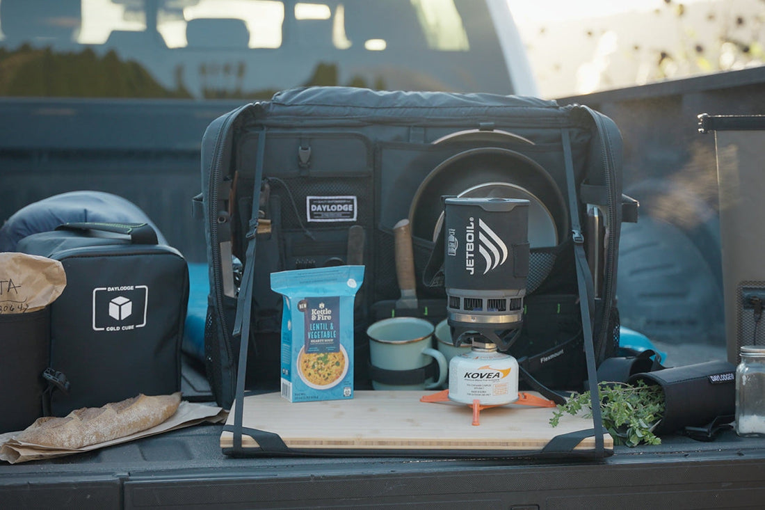 Close view of a loaded gear bay in a van with cases and a cook set laid out on a bamboo surface