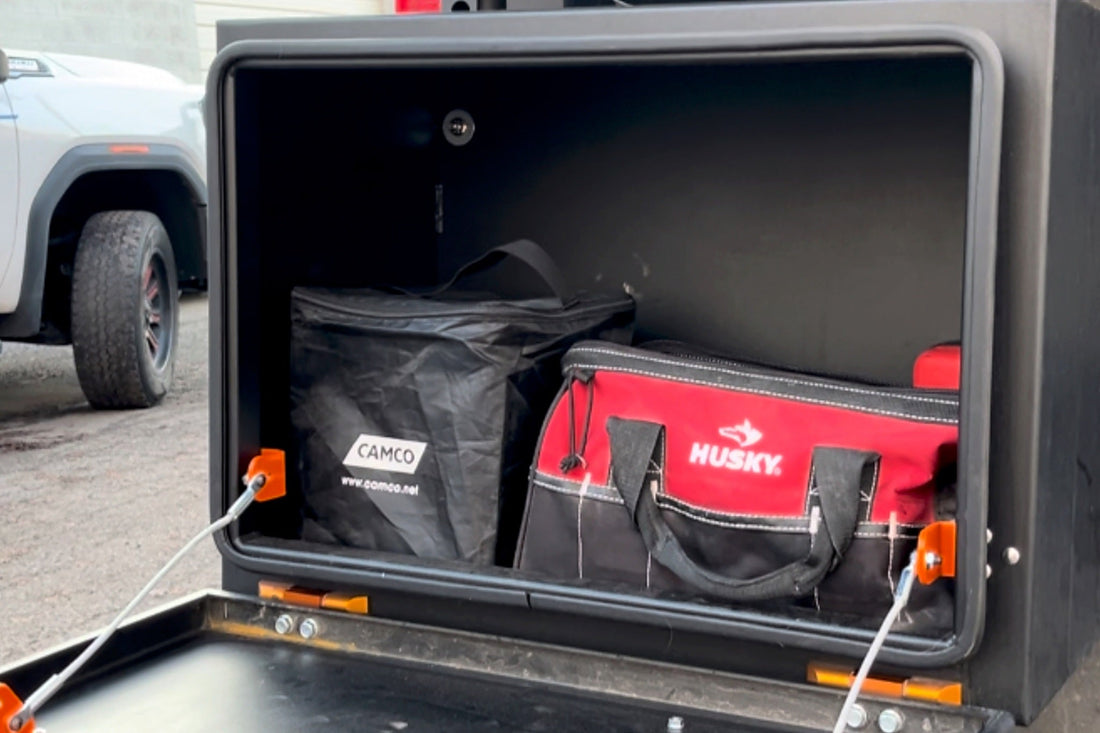 Close view inside an open exterior tool box on a van, tool bags stowed on the shelf