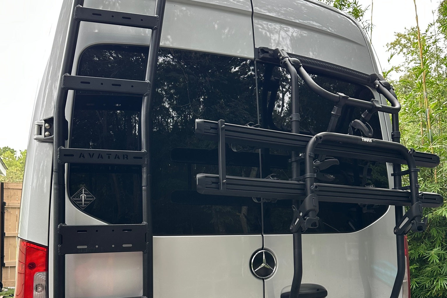A black rear door ladder and protection frame fitted to the rear of a Ram ProMaster