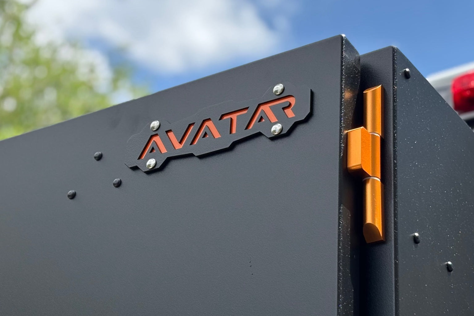 A lockable matte black aluminium case with T handle latches beside a van