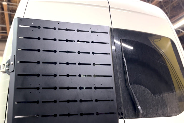 Powder coated mounting brackets, track sections and fixings laid out beside a van
