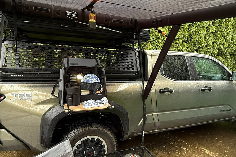 Vehicle shelter and camp kitchen set up over a truck bed