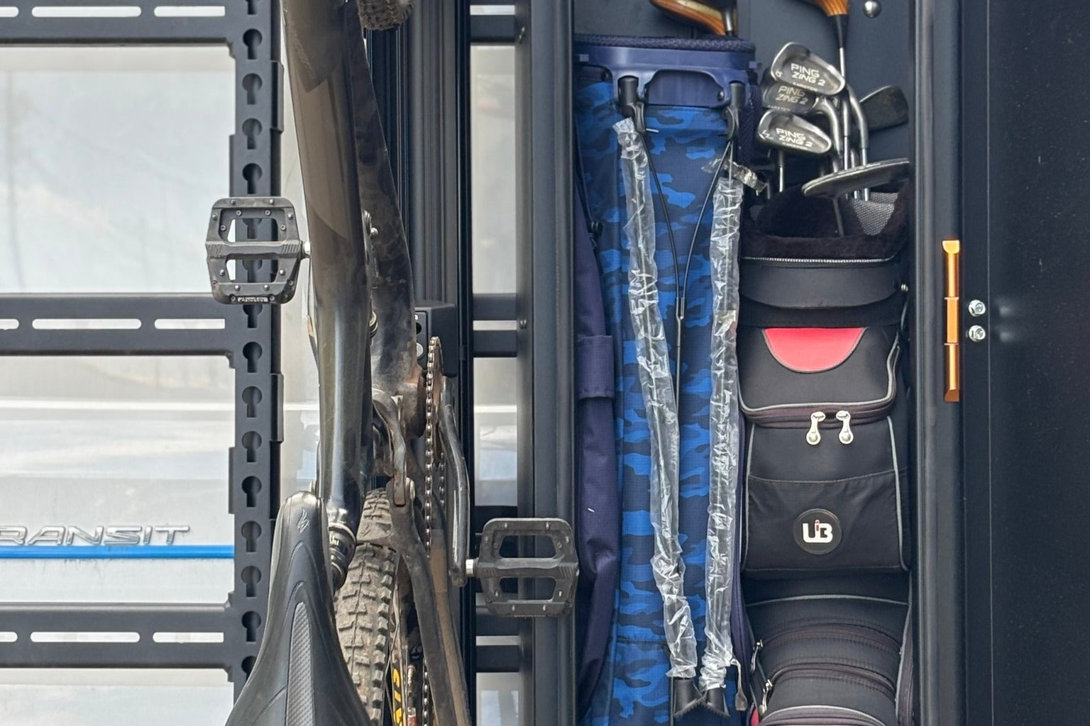 Mountain bike and golf bag stored upright in a van rack
