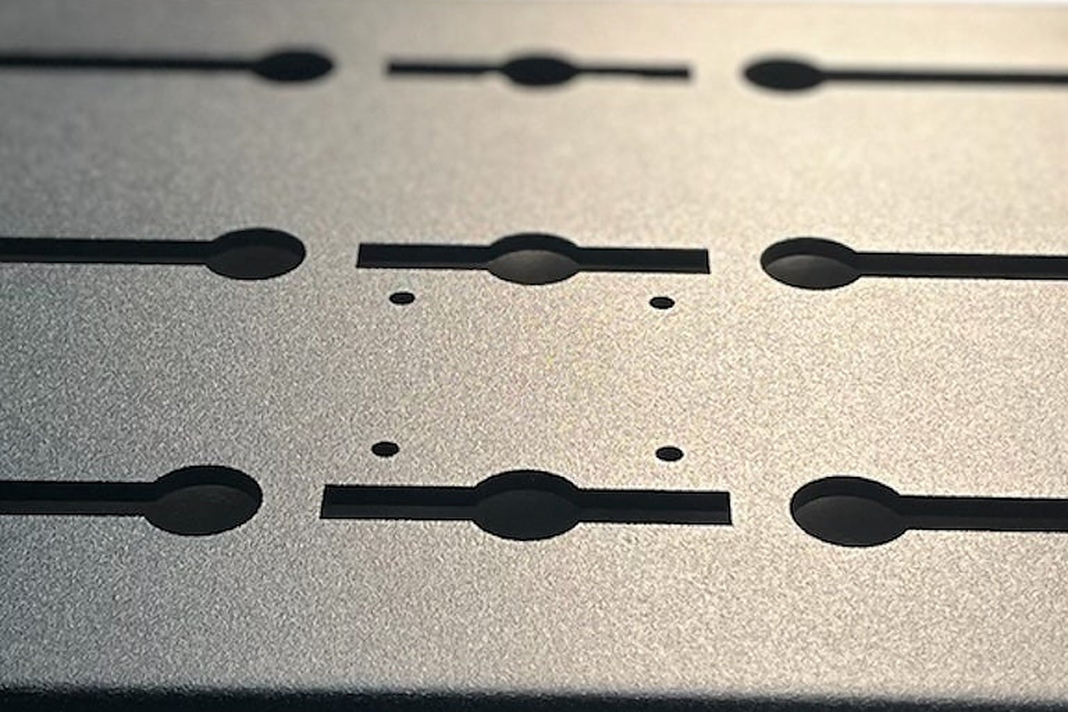 A laser cut black aluminium slotted panel shown as a product beside a van