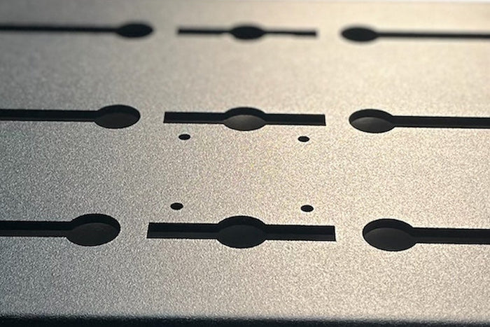 A laser cut black aluminium slotted panel shown as a product beside a van