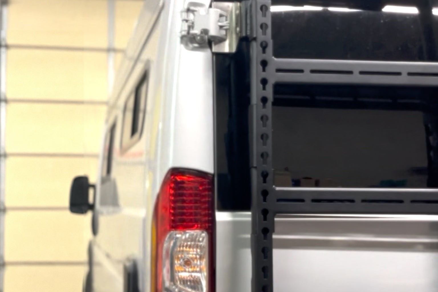 The cargo bay of a dark grey high roof van with shelving over the wheel arch and storage cases on the floor
