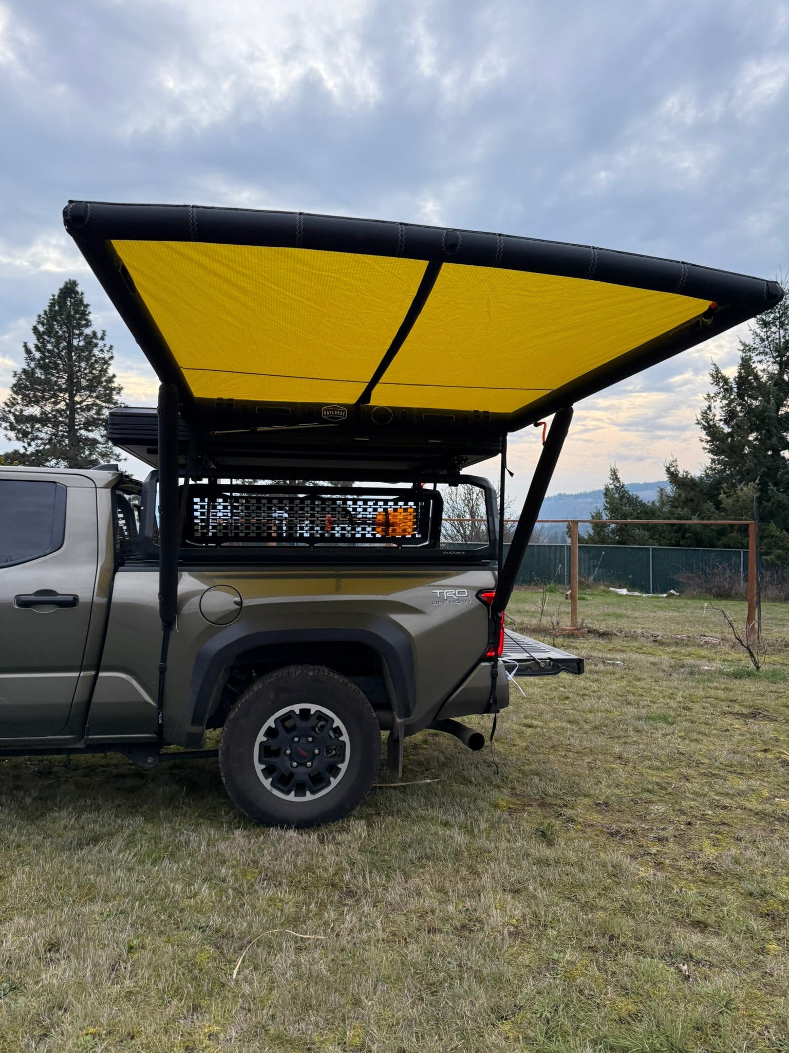 Angled view of the DAYLODGE AirHaven 40 Vehicle Shelter System, part of a vehicle based camp and travel setup