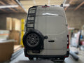 Angled view of the Avatar Offroad Rear Ladder with Tire Carrier for Vans, fitted to an overland van build